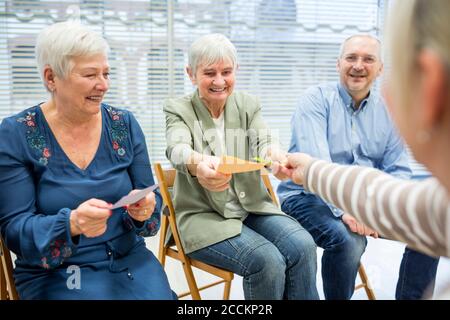 Seniors in retirement home attending group therapy using colorful paper cards Stock Photo