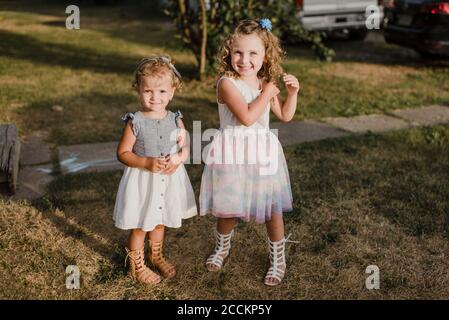 Portrait of two cute sisters standing on a meadow Stock Photo