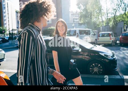 Couple talking while walking on city street during sunny day Stock Photo