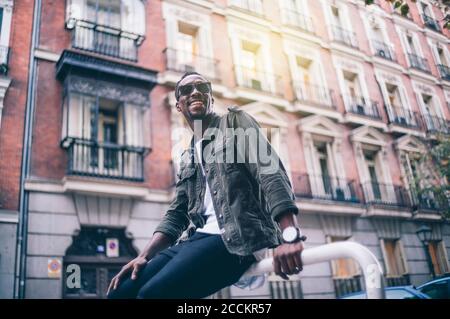 Smiling man wearing sunglasses sitting against building in city Stock Photo