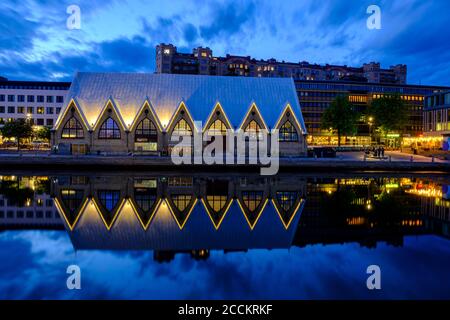 Sweden, Vastra Gotaland County, Gothenburg, Feskekorka fish market reflecting in coastal water at dusk Stock Photo