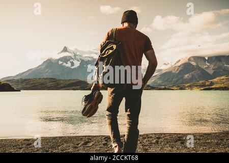 Man with backpack and shoe walking at lake Pehoe in Torres Del Paine National Park Patagonia, South America Stock Photo