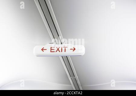 Exit sign on white airplane ceiling Stock Photo