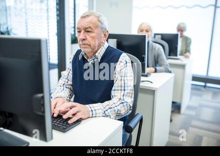 Active seniors attending computer course, working on PC Stock Photo