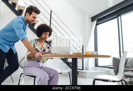 Mid adult couple using laptop at dining table in modern penthouse Stock Photo