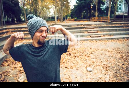 Man flexing muscles while standing in park during autumn Stock Photo