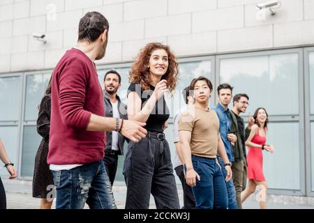Carefree male and female friends talking while walking in city Stock Photo