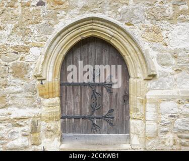 Old wooden door with large iron hinges in a wall of a church Stock Photo