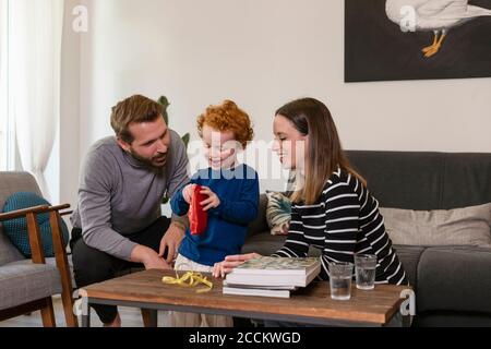Cute boy showing toy robot to smiling parents in living room at home Stock Photo