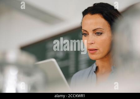Close-up of serious female owner using digital tablet in cafe Stock Photo