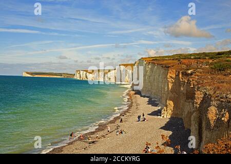 Seven Sisters Cliff, UK, 2020.  Tourists enjoying the shingle beach on a summers day after lockdown.  The cliffs are chalk and are located at the edge Stock Photo