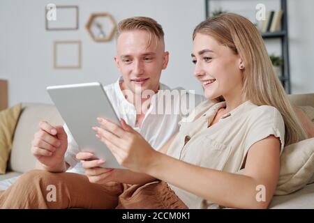 Contemporary young affectionate couple using tablet to watch online video Stock Photo