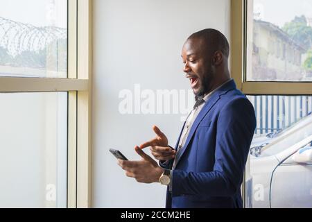 Young handsome african businessman feels excited as she operates her cellphone. Stock Photo