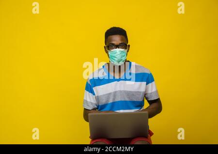 Young black entrepreneur male with a medical mask working on his laptop Stock Photo