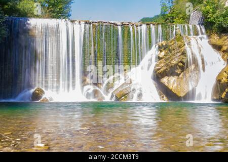 View of Waterfall along rocky wall Stock Photo