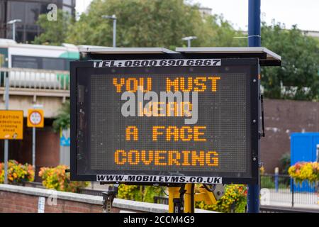 An electronic signboard outside a train station stating that you must wear a face mask during the coronavirus pandemic Stock Photo