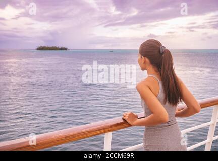 Luxury cruise vacation woman looking at exotic Tahiti landscape from boat deck at sunset. Elegant tourist young girl relaxing at view of ocean scenery Stock Photo