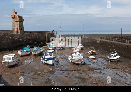 The picturesque harbour at Lynmouth in North Devon at low tide with boats on the sand and holidaymakers Stock Photo