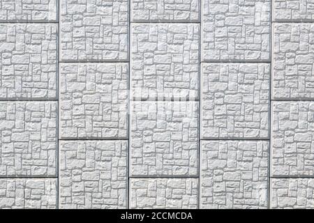 Light grey squares of patterned stone. The stones contain irregular rectangles. Bright sunlight. Stock Photo