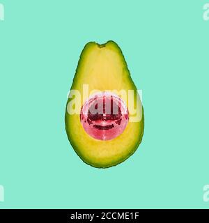 Avocado and disco ball on a colored background. Collage of modern art Stock Photo