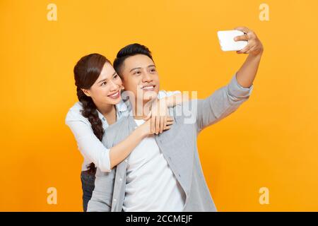 Photo of cheerful trendy charming cute nice couple of two people taking selfie smiling toothily hugging isolated yellow color background Stock Photo