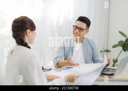 Two colleagues discussing data working and tablet, laptop with on on architectural project at construction site at desk in office Stock Photo