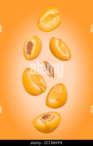 Falling apricots on the orange background. Flying fruits in the air. Stock Photo