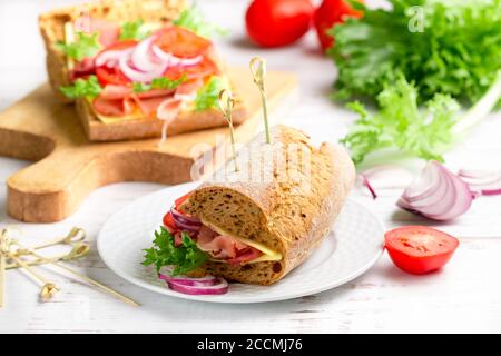 Rye grain bread sandwiches with cheese, meat, lettuce, tomatoes and red onions. Breakfast. Gourmet snack. Selective focus Stock Photo