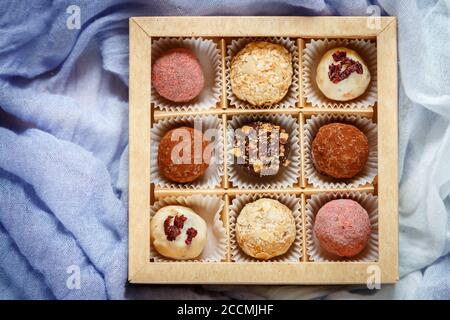 Assorted truffle set  of dark and white chocolate with almonds, hazelnuts and dried cranberries or cherries in a paper box. Candy.  Sweet gift. Holida Stock Photo