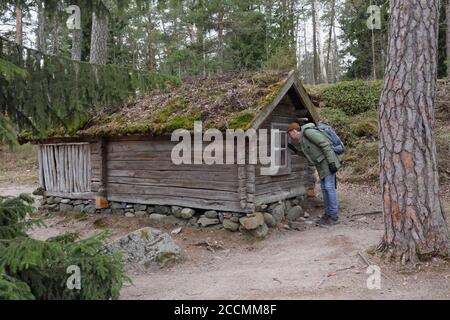 Tourist look in the window of a small wooden house in the open-air museum on Seurasaari island, Helsinki, Finland Stock Photo