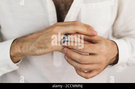 White man's hands putting on two rings with precious stones. Jewelry for men. Engagement ring. Stock Photo