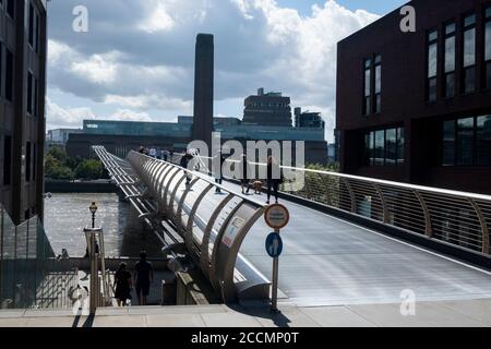 People walk and cycle across the Millennium Bridge, the famous wobbly footbridge crossing the Thames from St Pauls to the Tate Modern in London Stock Photo