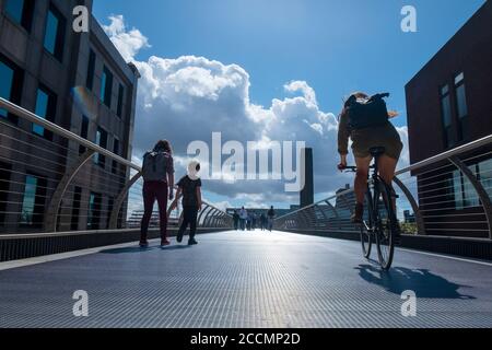 People walk and cycle across the Millennium Bridge, the famous wobbly footbridge crossing the Thames from St Pauls to the Tate Modern in London Stock Photo