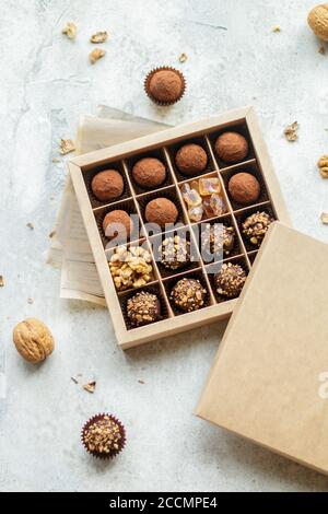 Set of chocolate truffles with nuts and cocoa. Tasty round candy. A delicious gift in a Kraft paper box. Holiday concept. Selective focus Stock Photo