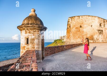 Old San Juan city tourist taking photo in Puerto Rico. Woman using phone taking pictures of ruins of watch tower of San Cristobal Castillo Fort, with Stock Photo