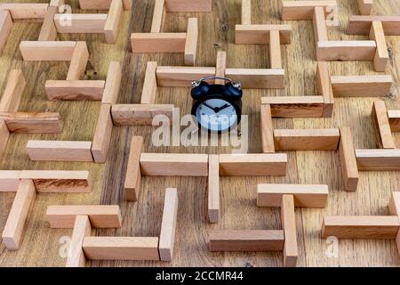 business concept, wooden maze model with clock in the center Stock Photo