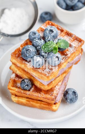 Traditional homemade Belgian (Viennese) waffles with fresh berries, blueberry souffle and powdered sugar. Delicious breakfast. Selective focus Stock Photo