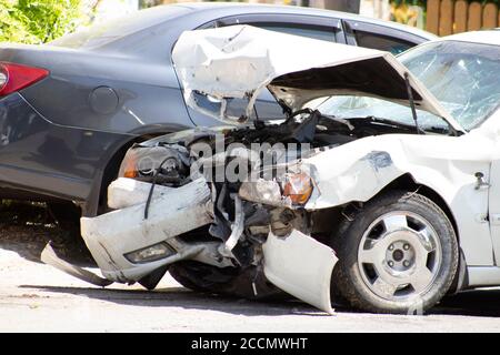 A road accident, a car that crashed, a white car on the road, cracks in the glass and a damaged bumper. Stock Photo