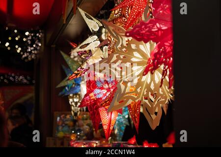 Night scenery, star cut-out paper hanging lantern in front of stall during Christmas market in Germany with blur background with bokeh of light. Stock Photo