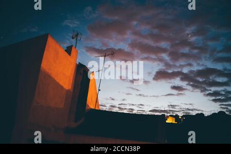 Wide-angle view of a dramatic late evening sky with beautiful cloudscape colored in lilac and blue colors in the background and Portuguese house Stock Photo