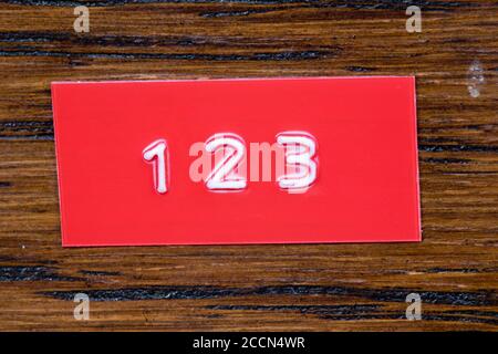embossed tape with the numerals 123 on a varnished wood background 2ccn4wr