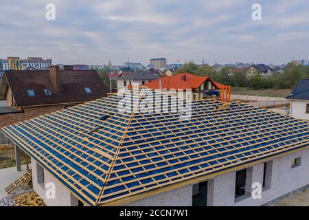 Residential house with wooden roof frame structure under construction. Unfinished brick building under development. Stock Photo
