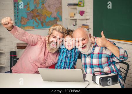 Happy three generations of men playing computer games. Man family. Man in different ages. Boy pupil with Father, Grandfather and grandfather. Stock Photo