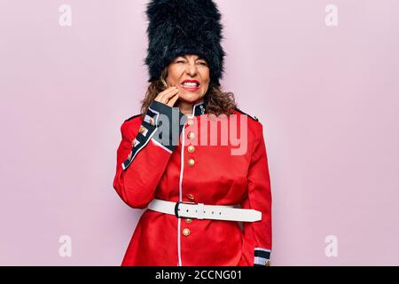 Middle age beautiful wales guard woman wearing traditional uniform over pink background touching mouth with hand with painful expression because of to Stock Photo