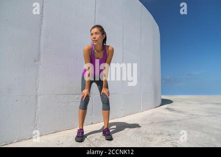 Runner woman tired resting catching breath during cardio workout. Motivation and determination athlete girl ready to run Stock Photo