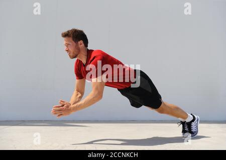 Clap pushup fitness man doing plyometrics push-up explosive workout for muscles training. Athlete working out on gym floor Stock Photo