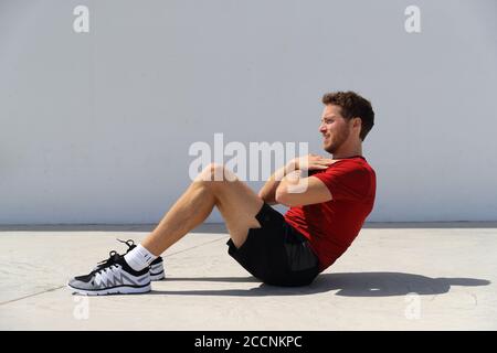 Fitness man doing sit-ups bodyweight floor exercises at gym. Sport athlete doing exercise training abs muscles doing crunches working out to get six Stock Photo
