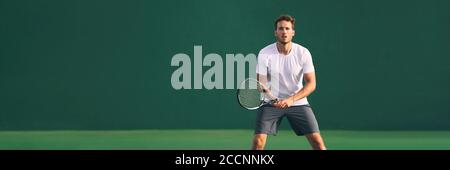 Tennis player man focused in ready position. A male athlete waiting for serve on panoramic green background banner. Challenge and concentration in Stock Photo