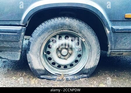 flat tyre of old car outdoors, dirty collapsed tyre close up Stock Photo