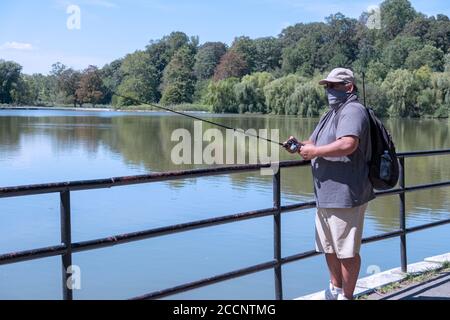 A middle aged man wearing a neck scarf fishes in the Lake at Kissena Park in Flushing, Queens, New York City. Stock Photo